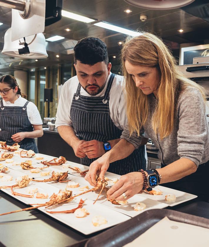 Imagen secundaria 2 - Foto de familia de los participantes, y Gorka Txapartegi y Lidia Olaizola en plena faena en los fogones.