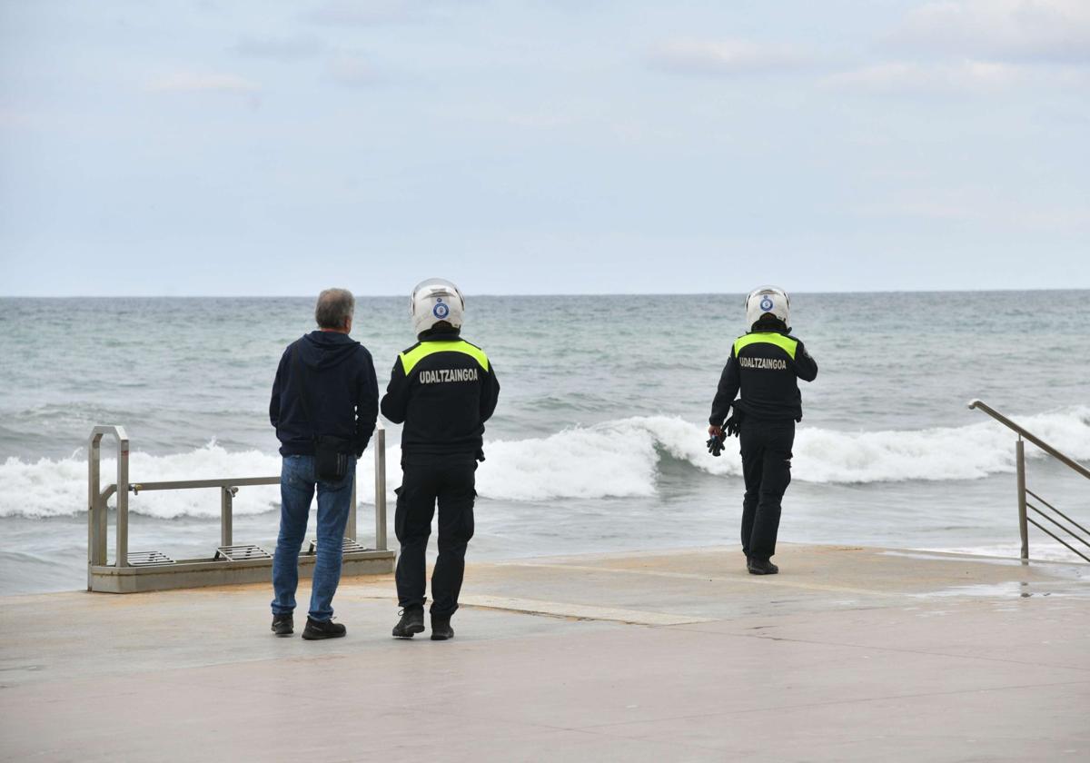 Dos guardias municipales de Zarautz observan el oleaje en la playa zarauztarra.