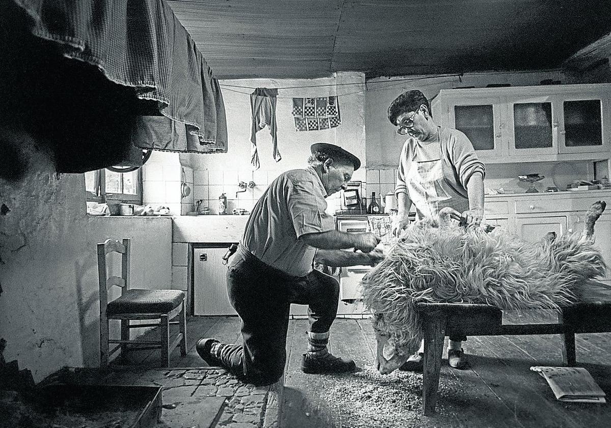 Imagen principal - Arriba: Pako Bastida Azpiazu y Julieta Zubizarreta Albizu despiezando una oveja en la cocina del caserío Katalotza. Abajo, izquierda: María Arrizabalaga en una imagen cotidiana, en el caserío Urrategi.. Abajo, derecha: El autor, fotografiándose a sí mismo a través de un espejo. 