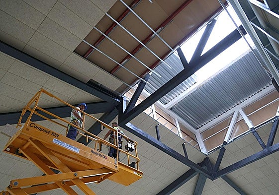 Dos obreros realizan trabajos en la cubierta del edificio Pescadería de la Bretxa.