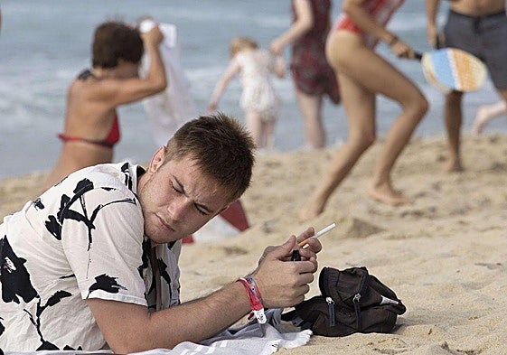 Un joven sostiene un cigarro en una playa en San Sebastián.