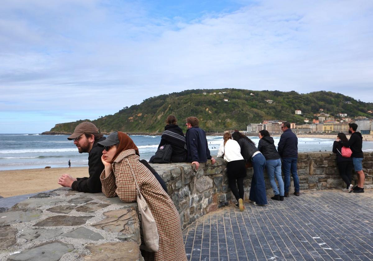 Un grupo de personas disfruta del buen tiempo cerca del espigón de la playa de la Zurriola.