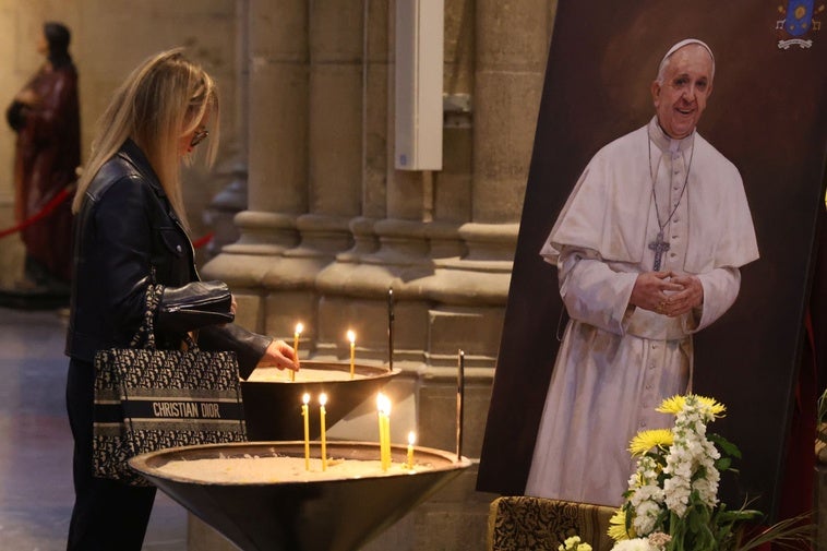 Una mujer enciende una vela frente al retatrato del Papa Francisco, que se encuentra dentro de la catedral del Buen Pastor en Donostia.