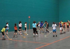 Niños practicando hockey en un frontón.