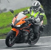 Una moto circula sobre una carretera mojada, terreno delicado para frenar.