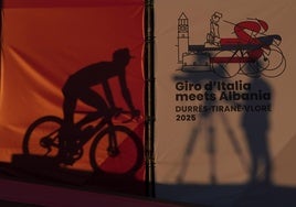 Un corredor pasa tras un cartel anunciador de la salida del Giro en Albania.