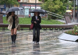 Dos jóvenes se refugian de la lluvia ayer en Irun.