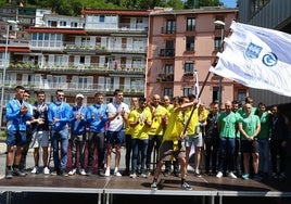 Gorka Aranbarri ondea la bandera tras imponerse Orio en el Campeonato de Gipuzkoa de trainerillas, con los remeros de Donostiarra y Hondarribia acompañándoles.