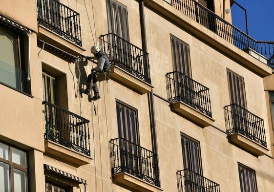 Un empleado trabaja en la reforma de una fachada.