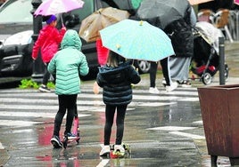 Dos niñas se dirigen a un paso de cebra montadas en sus patinetes.