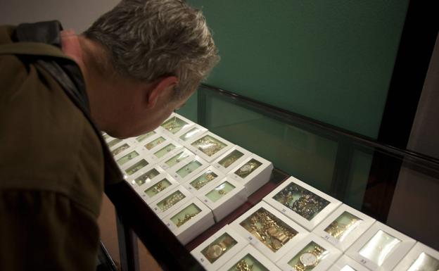 Un hombre observa joyas de una subasta a finales del pasado siglo.