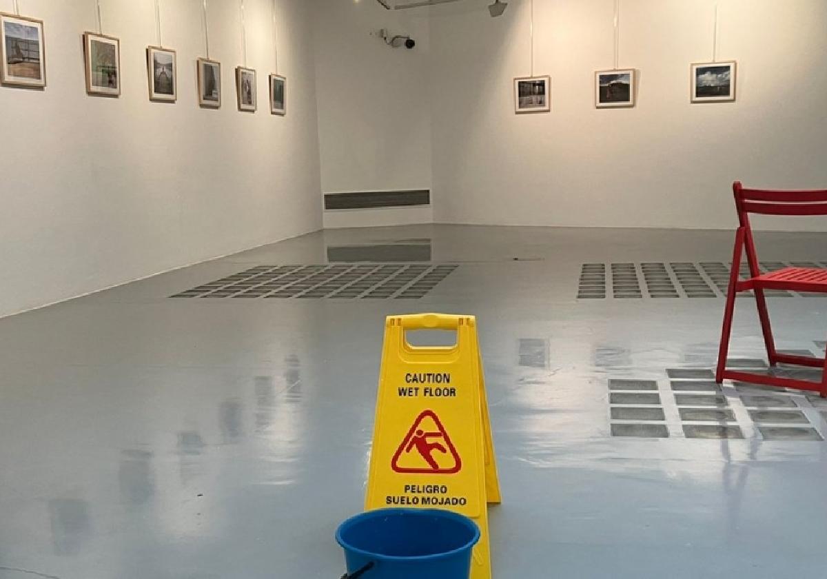 La señal de aviso de goteras acota un espacio de la sala.