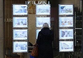 Una mujer consulta las ofertas en el escaparate de una inmobiliaria de Donostia.