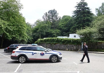 Un agente se dirige a un coche patrulla en el parking del monte Ulia.