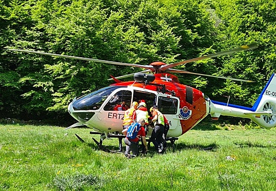 Los servicios de emergencia trasladan al corredor accidentado hasta el helicóptero para ser evacuado.