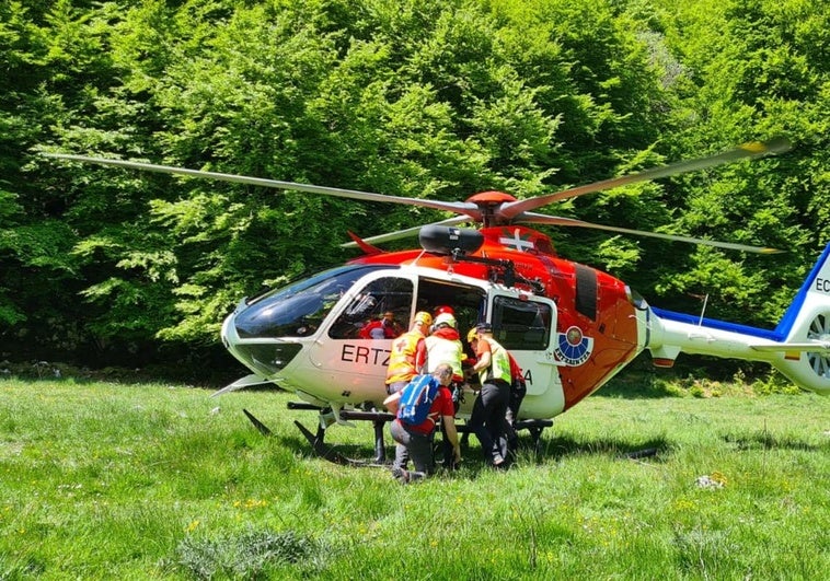 Los servicios de emergencia trasladan al corredor accidentado hasta el helicóptero para ser evacuado.