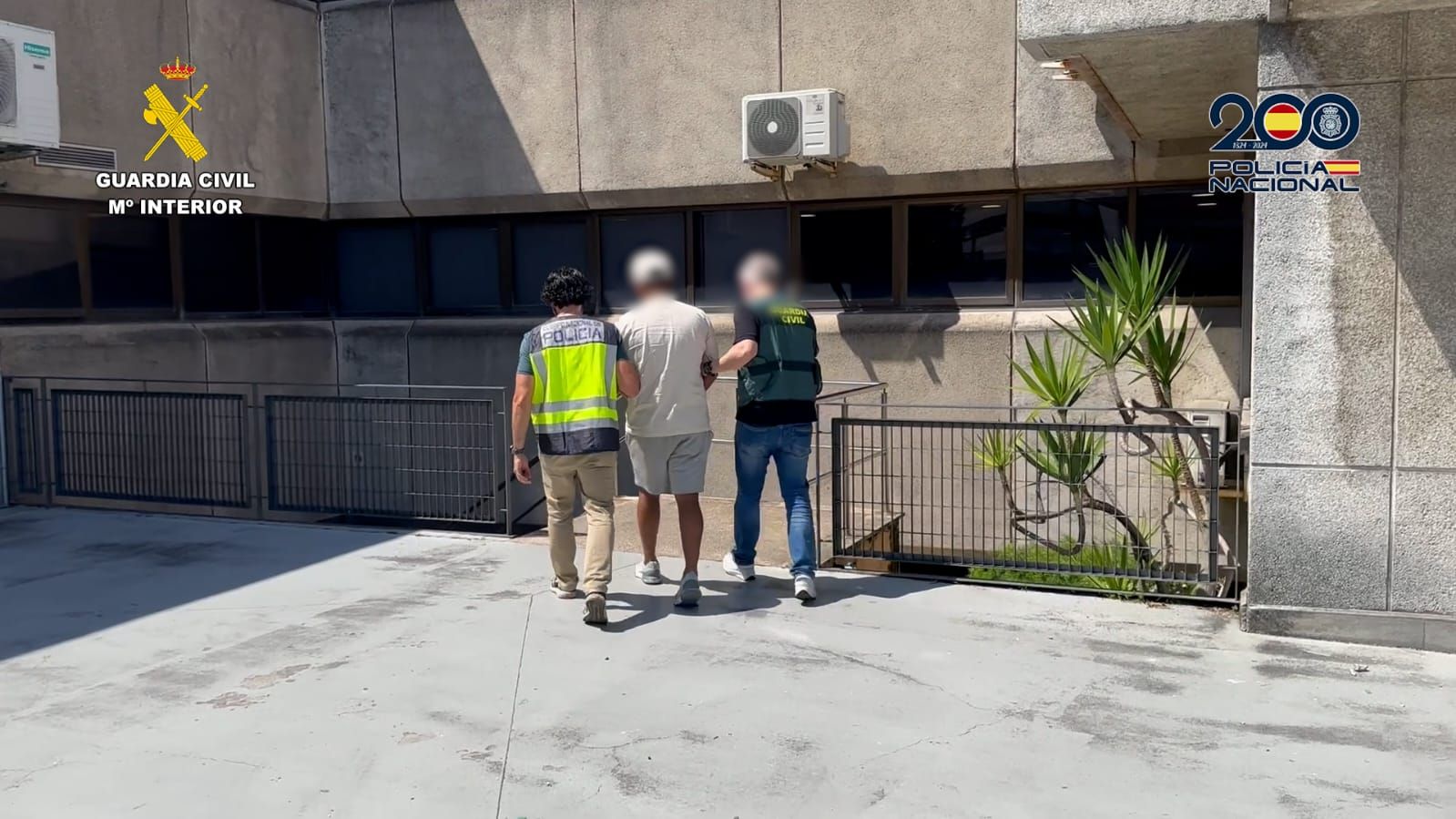 Uno de los detenidos, flanqueado por agentes de la Policía Nacional y Guardia Civil.