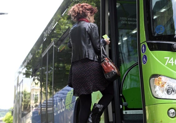 Una mujer se sube a un autobús de Dbus con la Mugi en la mano.