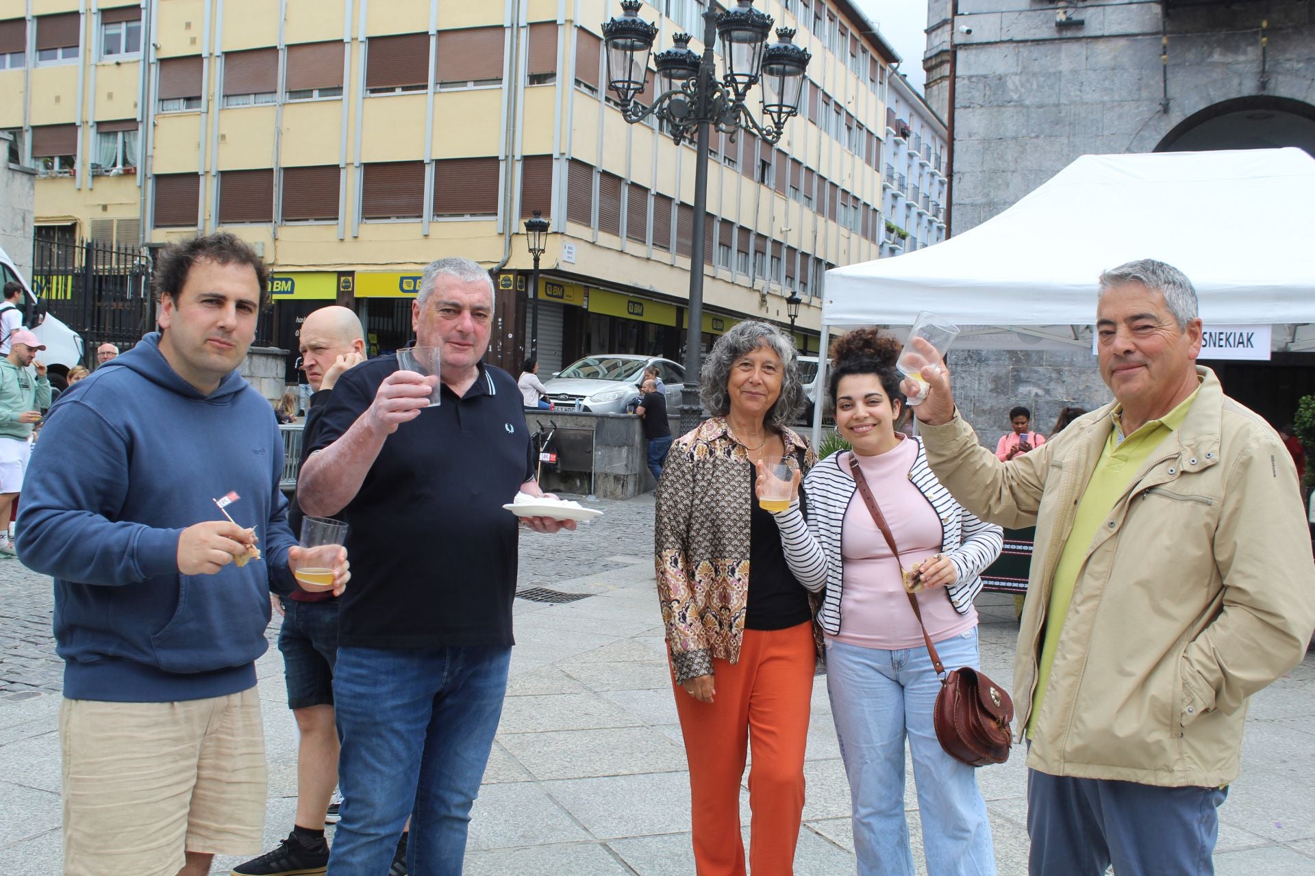 Imagen principal - Lagun kuadrilla gustura, txekor erre pintxoak eta edalontziak hartuta, eta baserritarrek jarritako postuak.