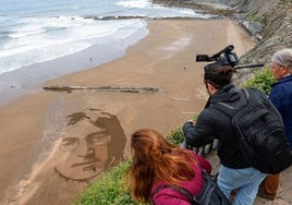 El artista Germán Cedano trabaja en un retrato del músico John Lennon creado en la playa de Itzurun de Zumaia (Gipuzkoa).