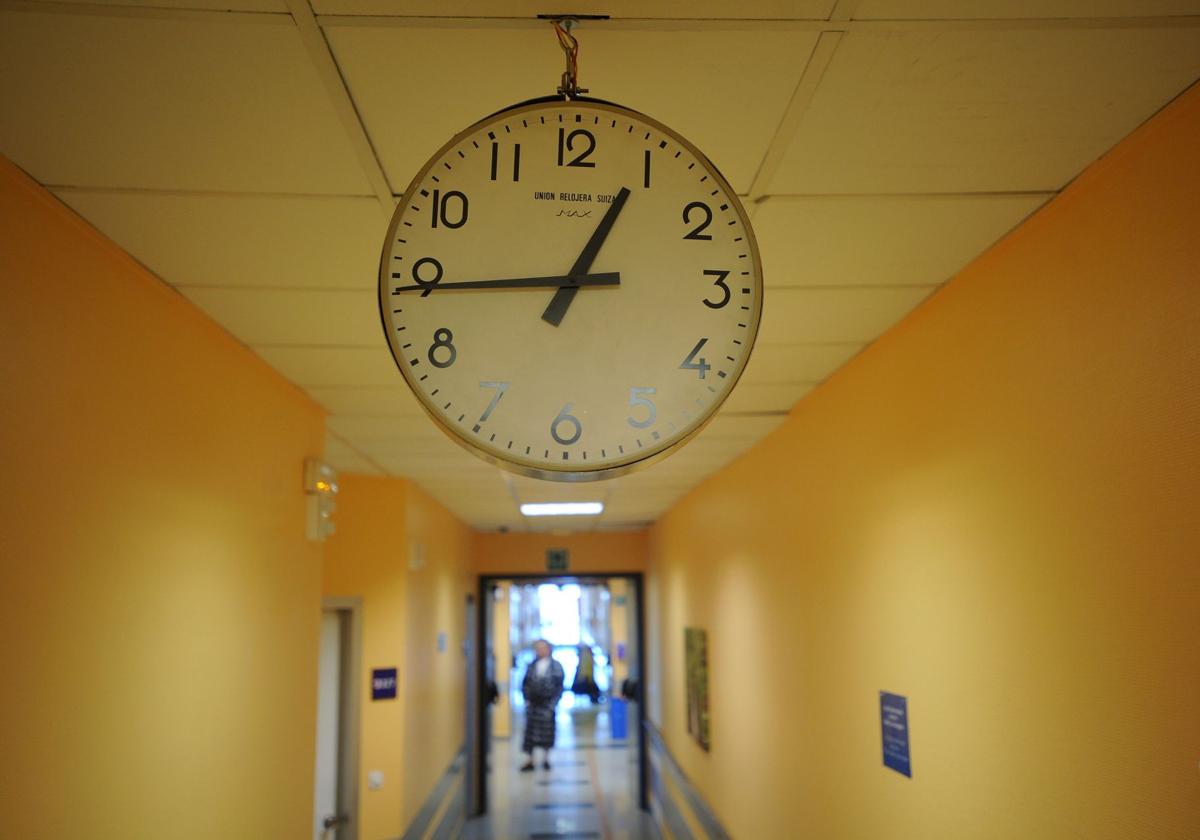 Un reloj indica la hora en el pasillo de un hospital con camas para cuidados paliativos.