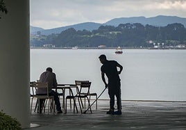 Un camarero trabaja en una terraza ante un cliente.