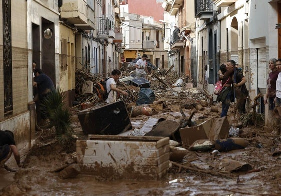 Varias personas trabajan en labores de limpieza y desescombro en una calle del municipio de Paiporta, en Valencia, uno de los más afectados por la DANA del pasado 29 de octubre.