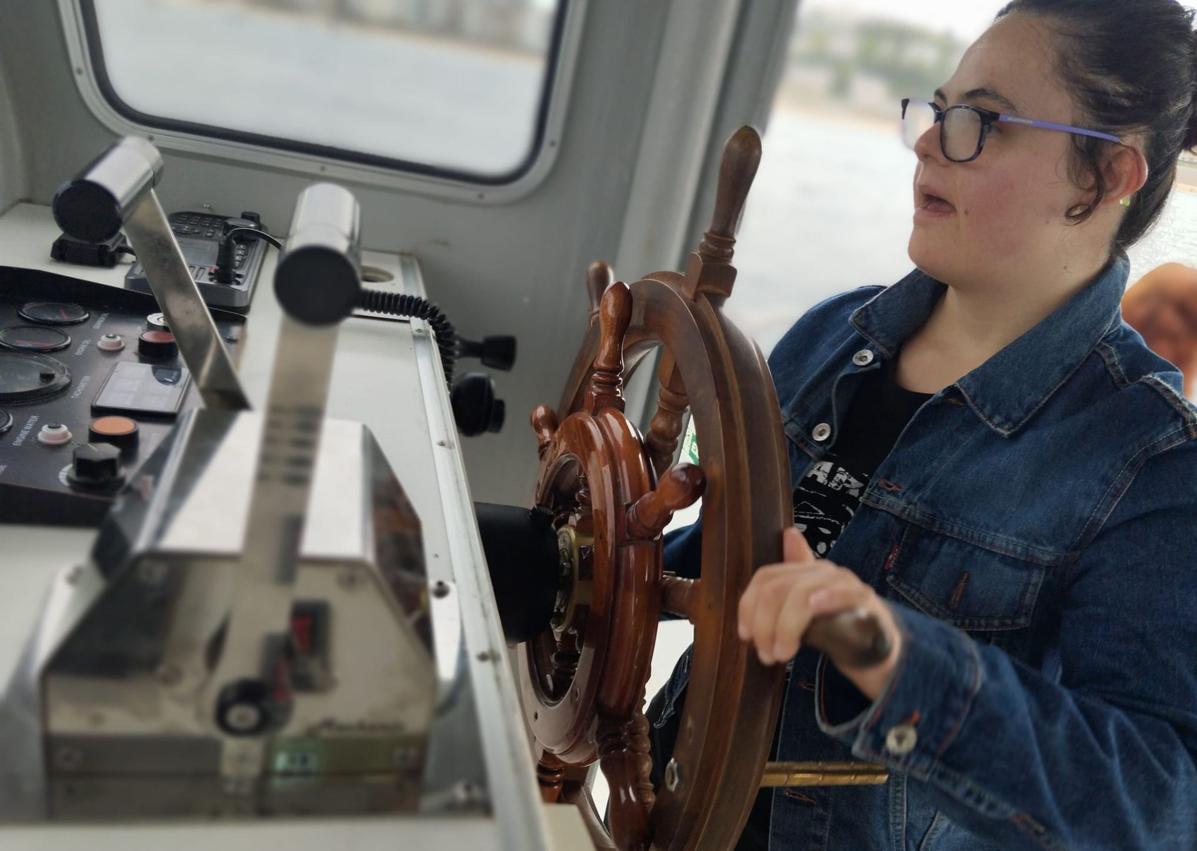 Imagen secundaria 1 - Iñaki Lahortiga con su camiseta, Ainhoa Suescun con el timón del barco en Donostia e Iñaki Alforja, director del documental.