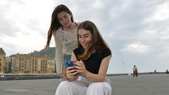 Maddi Garate, estudiante que ha sacado la mejor nota de Selectividad de Euskadi, consulta su calificación en el teléfono móvil bajo la mirada de una amiga este miércoles en San Sebastián.