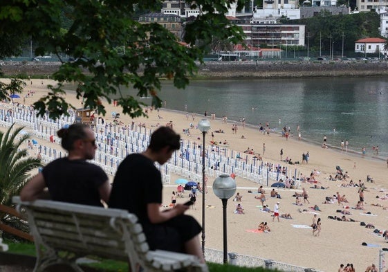 Una pareja se resguarda del calor a la sombra de un árbol en Donostia