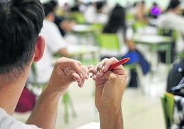 Un joven, sin relación con la información, sujeta un bolígrafo mientras atiende en clase.
