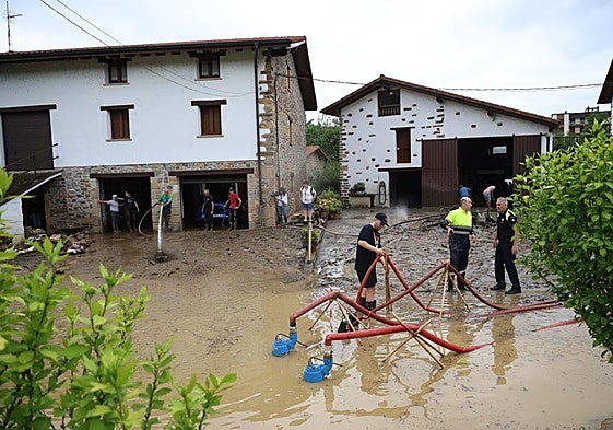 Operarios municipales y vecinos con las bombas de desagüe en una zona de baserris afectada en Lazkao.