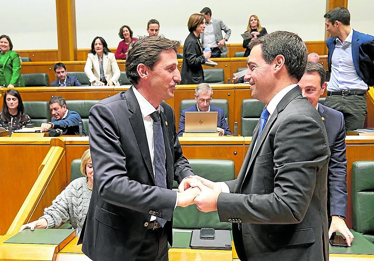 El consejero de Hacienda y Finanzas, Noël d'Anjou, estrecha las manos del lehendakari, Imanol Pradales, en el Parlamento Vasco.