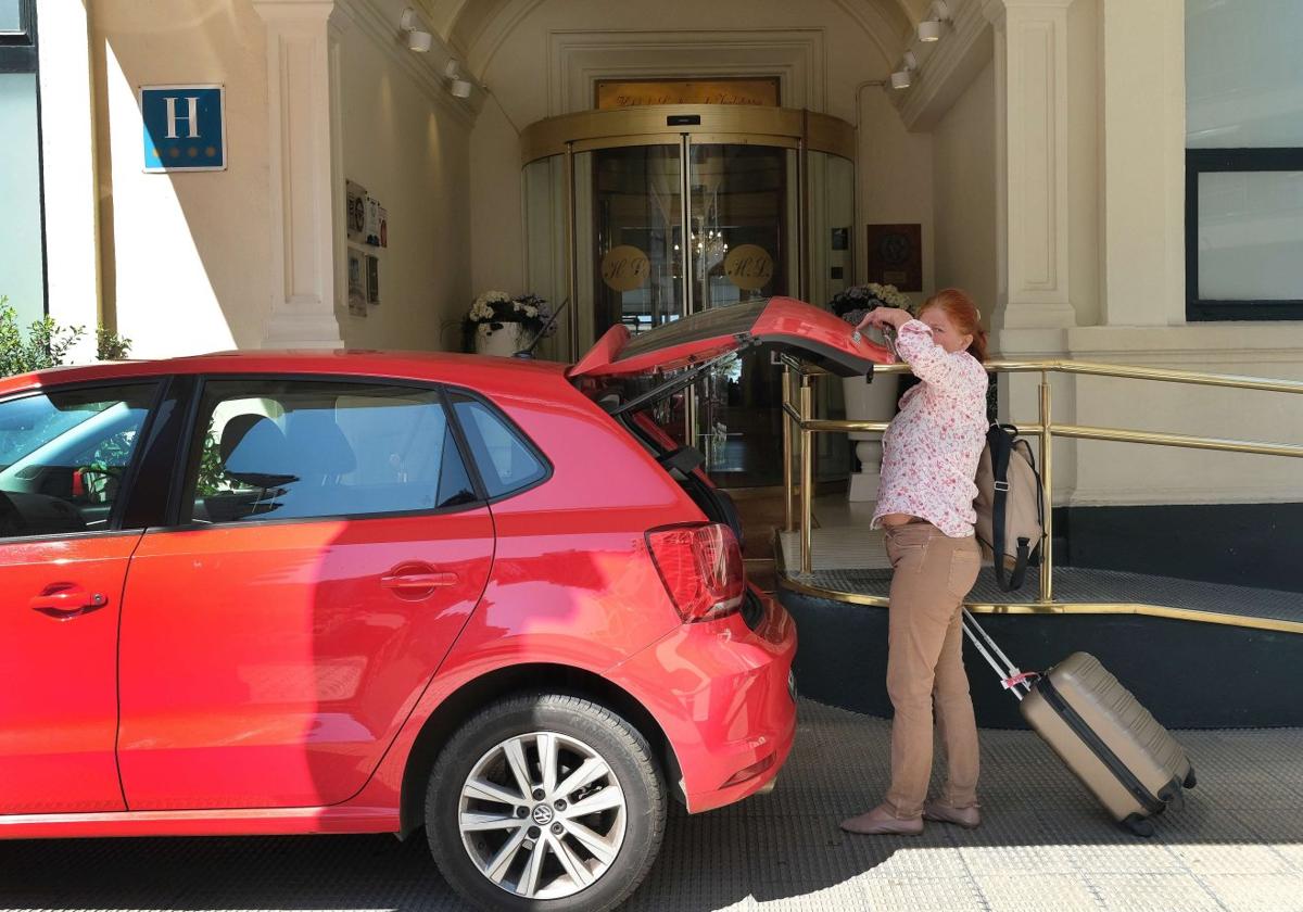 Una mujer saca su maleta del coche antes de acceder a un hotel de San Sebastián.