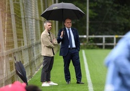 Aperribay, junto a Erik Bretos en el entrenamiento de la Real de este lunes, protegidos de la lluvia por un paraguas
