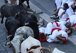 Varios corredores se protegen tras caer al paso de los toros de la ganadería Cebada Gago durante el segundo encierro de los Sanfermines este martes, en Pamplona.