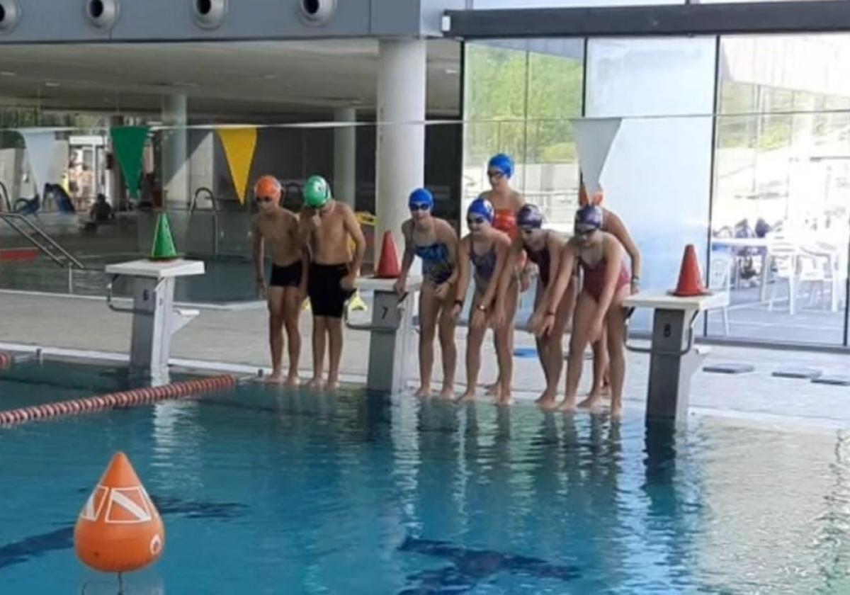 Niños y niñas se preparan para saltar a la piscina del polideportivo.
