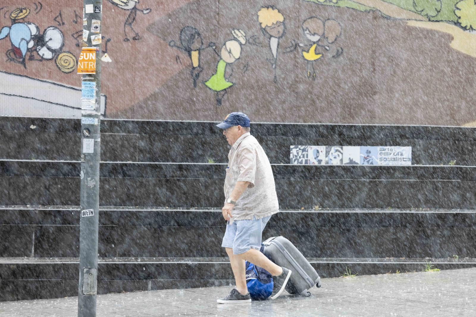 Un hombre camina bajo la lluvia este miércoles por la mañana en la plaza Nestor Barrenetxea de Donostia