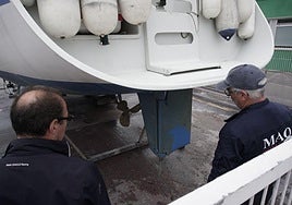 Dos personas observan en el Puerto de Getaria el timón del velero Azurea, dañado tras el ataque de un grupo de orcas este lunes en aguas de Gipuzkoa.