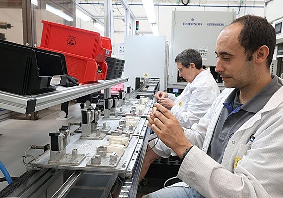 Dos trabajadores del área industrial de Gureak ensamblan la pieza que va en el retrovisor de los Porche para iluminar el suelo cuando se abre la puerta.