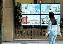 Una joven frente el escaparate de una agencia inmobiliaria