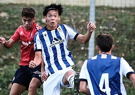 Kazunari Kita, pugnando por un balón aéreo con un rival.
