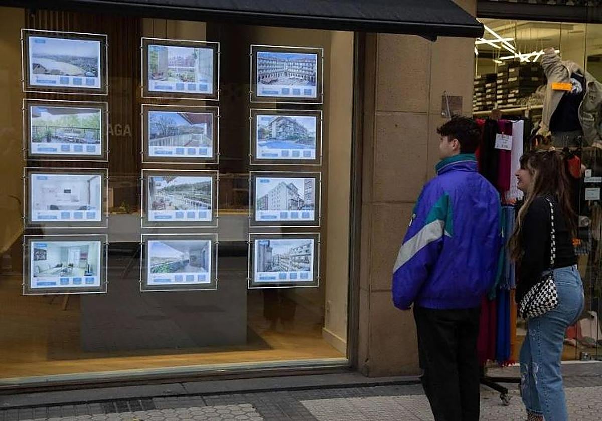 Jóvenes miran pisos en alquiler en una agencia inmobiliaria de San Sebastián.