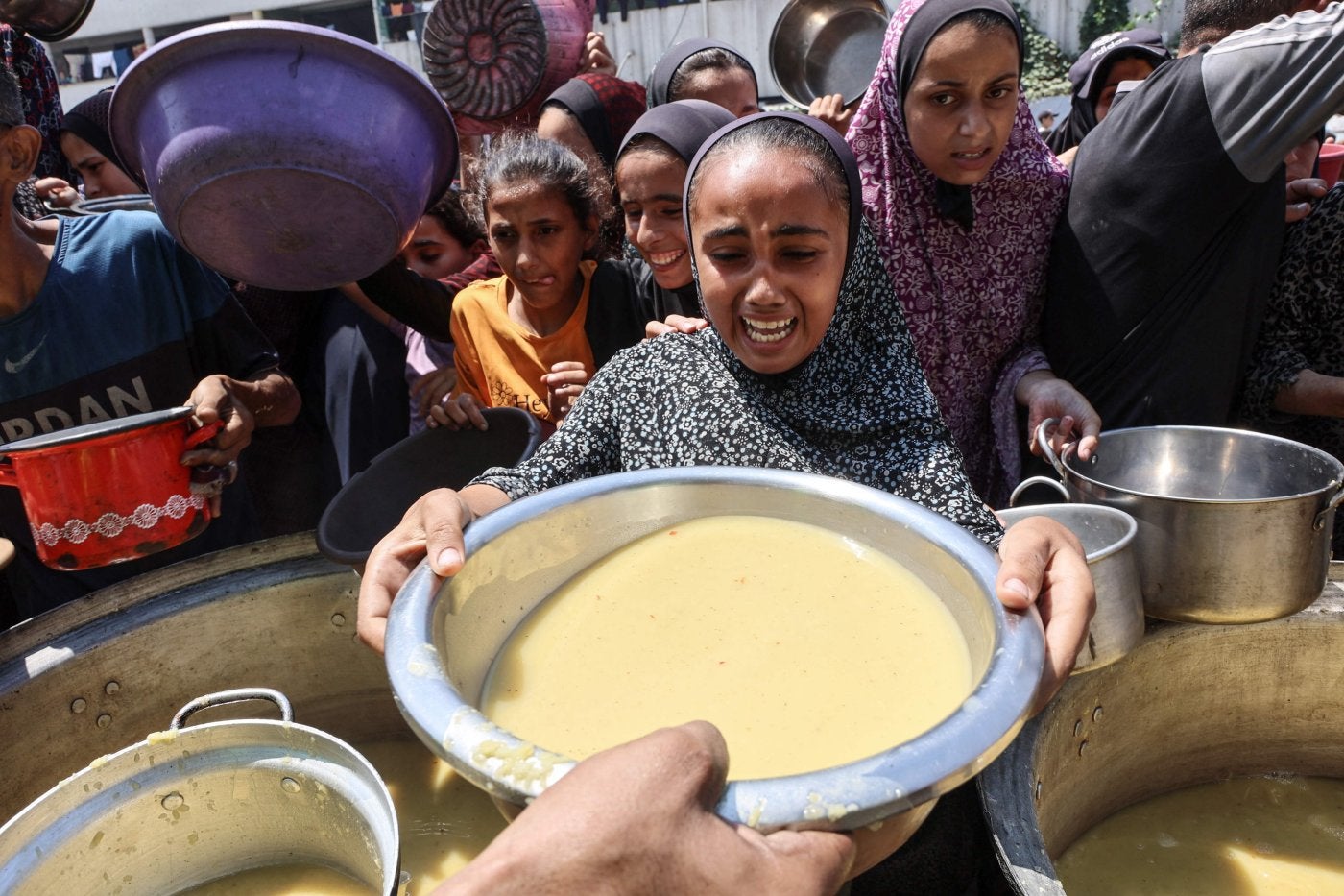 Una niña recibe sopa de lentejas en un centro de distribución de comida en la Ciudad de Gaza.