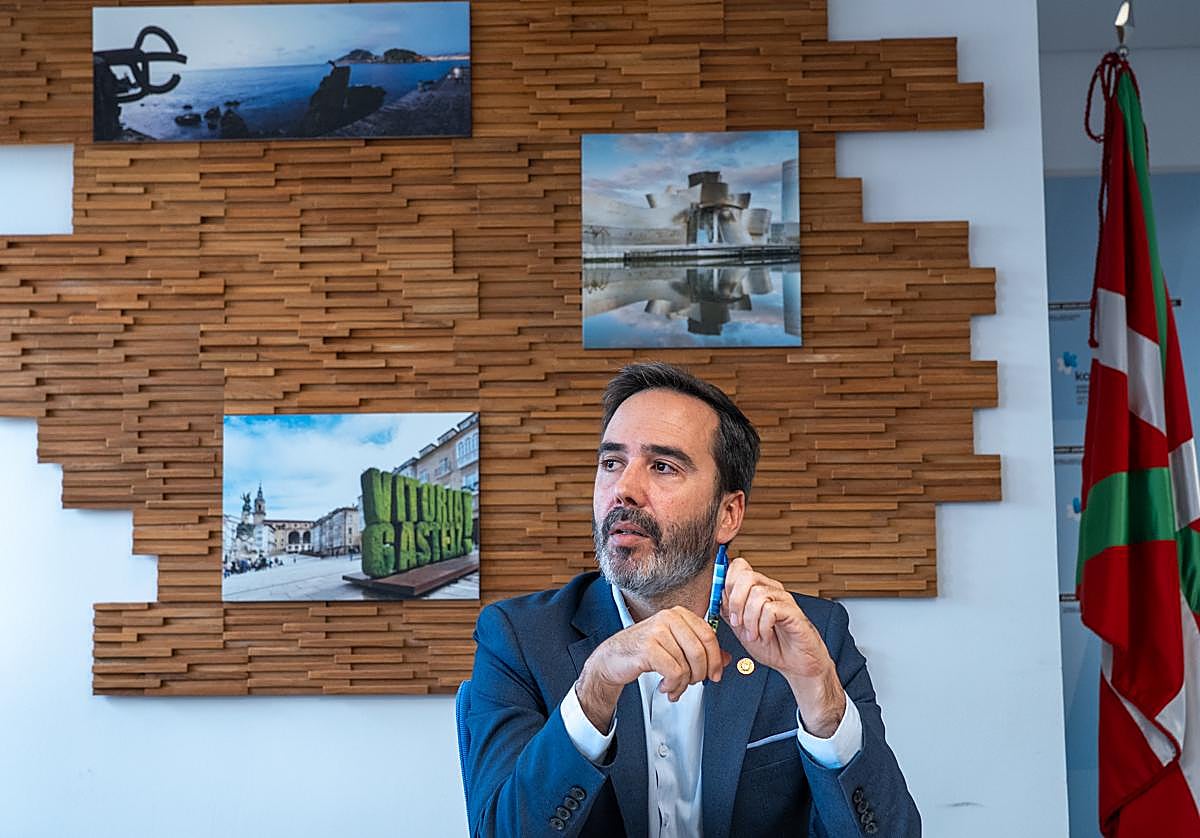 Javier Hurtado, durante la entrevista en una sala con imágenes de atractivos turísticos, entre ellos el Peine del Viento de Donostia.