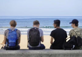 Cuatro jóvenes charlan ante la playa de La Zurriola.