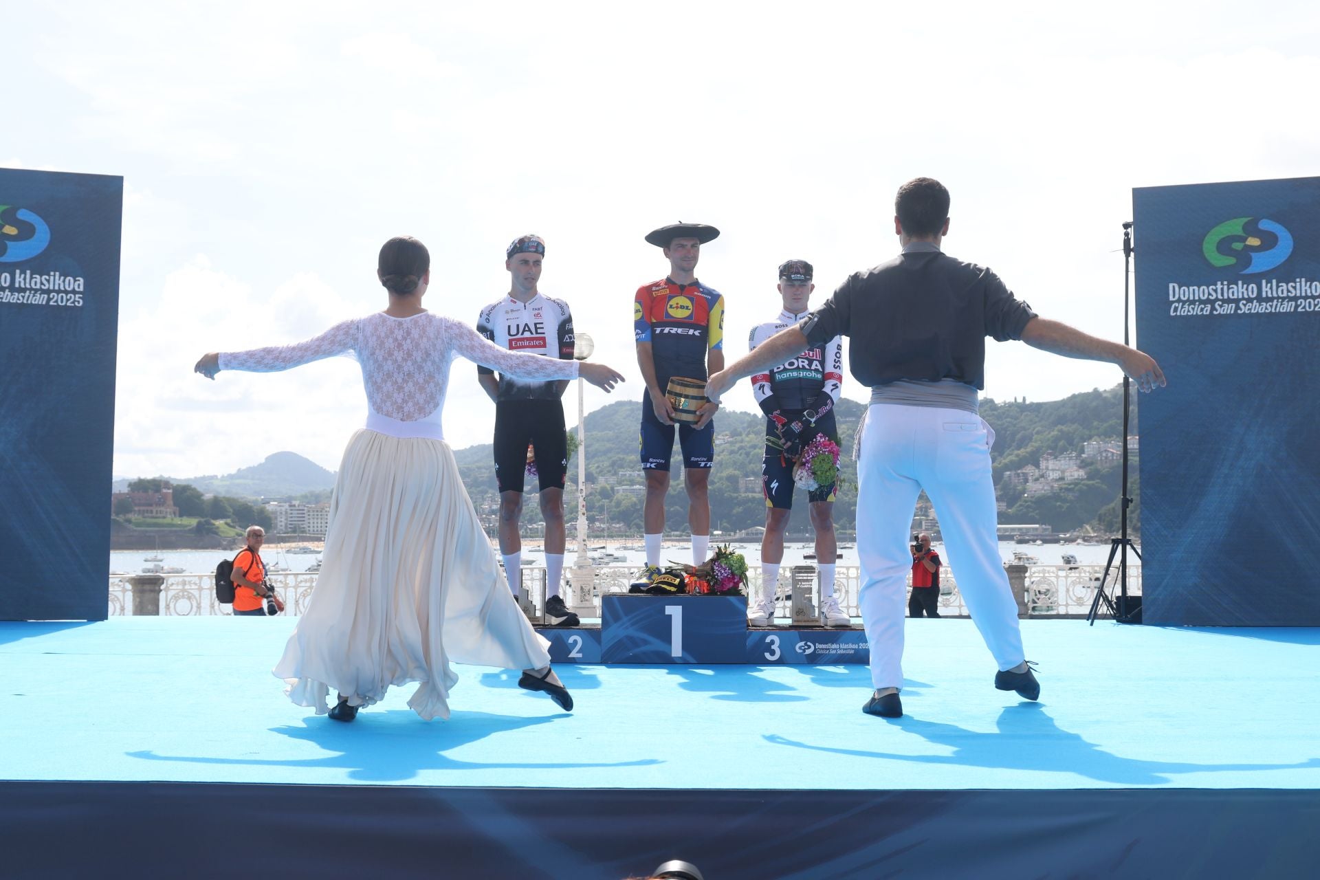 Dos dantzaris dedican un aurresku a los tres primeros clasificados Christen, Ciccone y Van Gils, ayer durante el podio en Alderdi Eder.