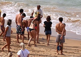 Un grupo de bañistas observa una carabela portuguesa en una playa donostiarra.