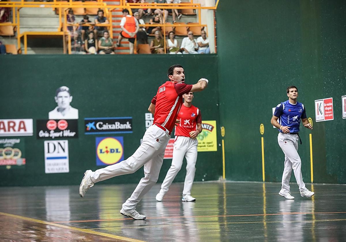 Altuna III golpea la pelota desde el ancho ante Rezusta y Zabaleta en la semifinal del Ogueta.