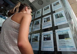 Una joven mira el escaparate de una inmobiliaria en Donostia.